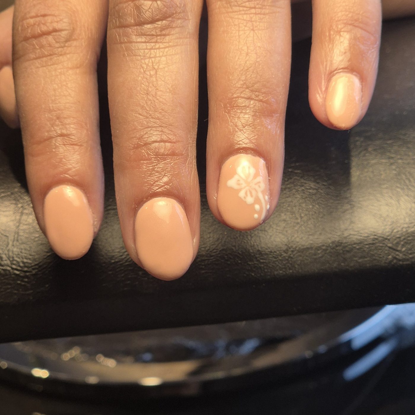 Naturel gekleurde nagels met een witte bloem als nail art op een nagel